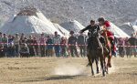 A woman chases a man on horseback at the World Nomad Games.