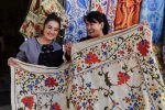 Smiling vendors show off their beautiful embroidered suzani in Uzbekistan. Photo credit: Phil Kidd
