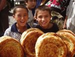 Kids posing with bread at a market in Uzbekistan.