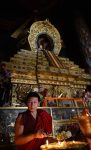 Tibetan monk tending a yak butter lamp. Photo credit: Phil Kidd