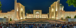 A large crowd gathers at night in Registan Square, Samarkand, Uzbekistan