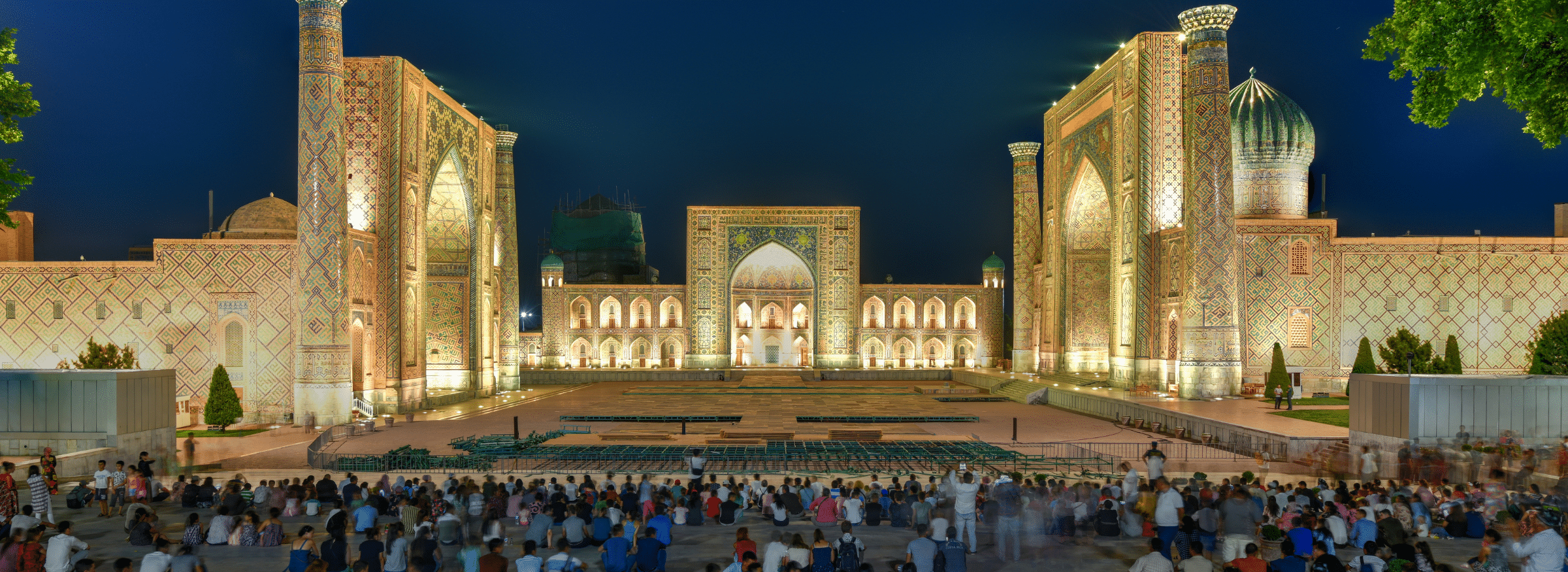 A large crowd gathers at night in Registan Square, Samarkand, Uzbekistan