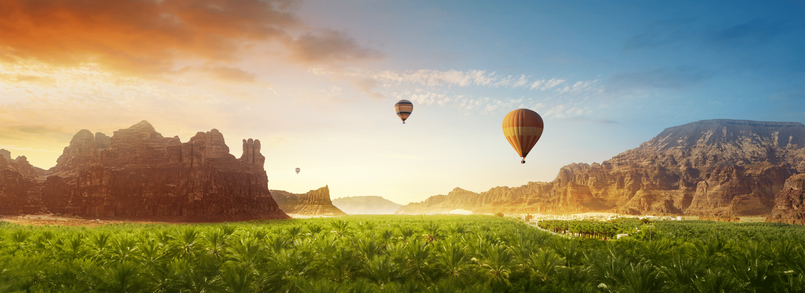 Hot air balloons rise above a lush Al Ula valley, surrounded by rocky cliffs under a vivid sunrise sky.